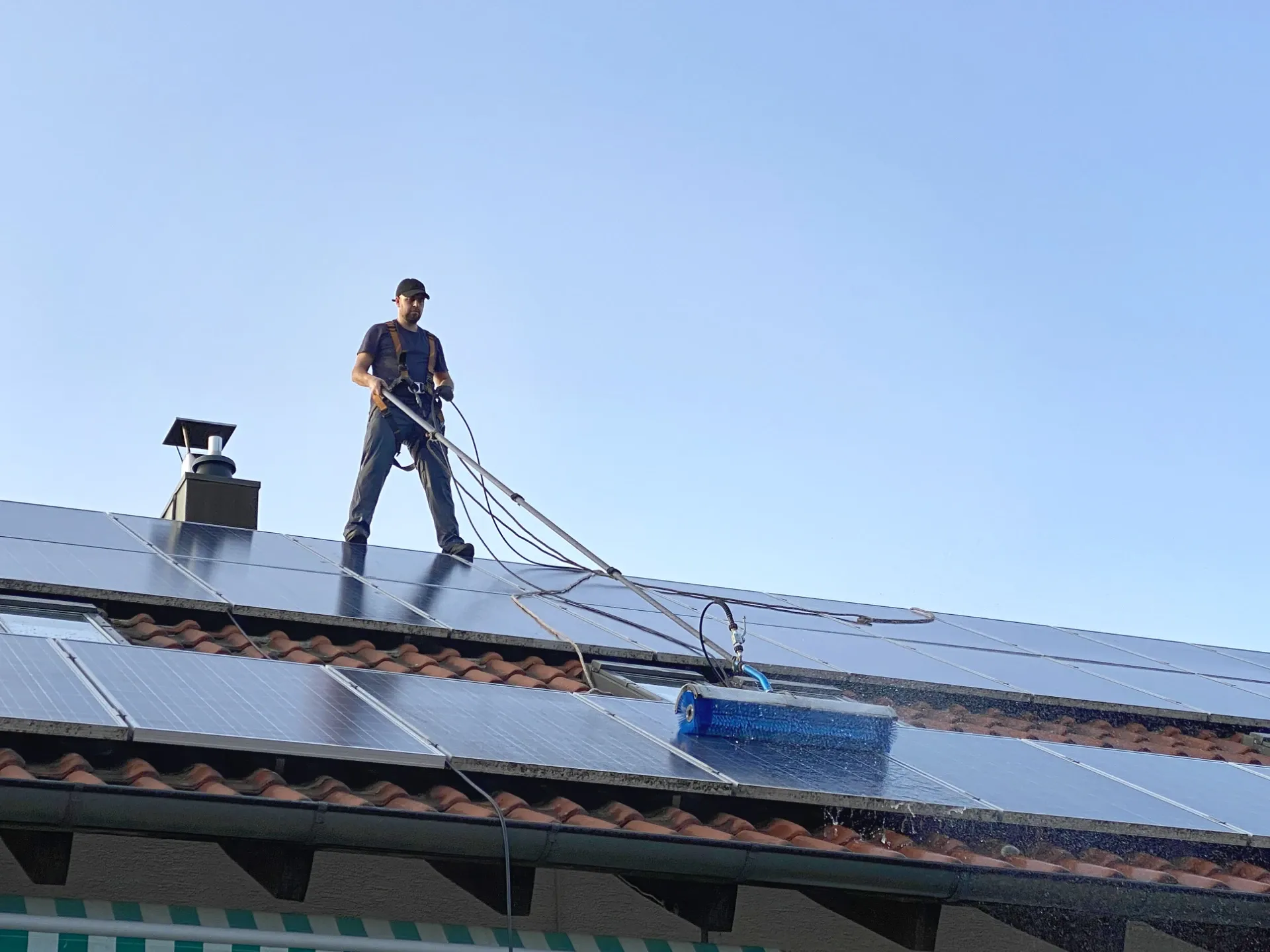 Photovoltaikreinigung in der Nähe - Solarninjas-Mitarbeiter reinigt Solarmodule auf einem Dach.